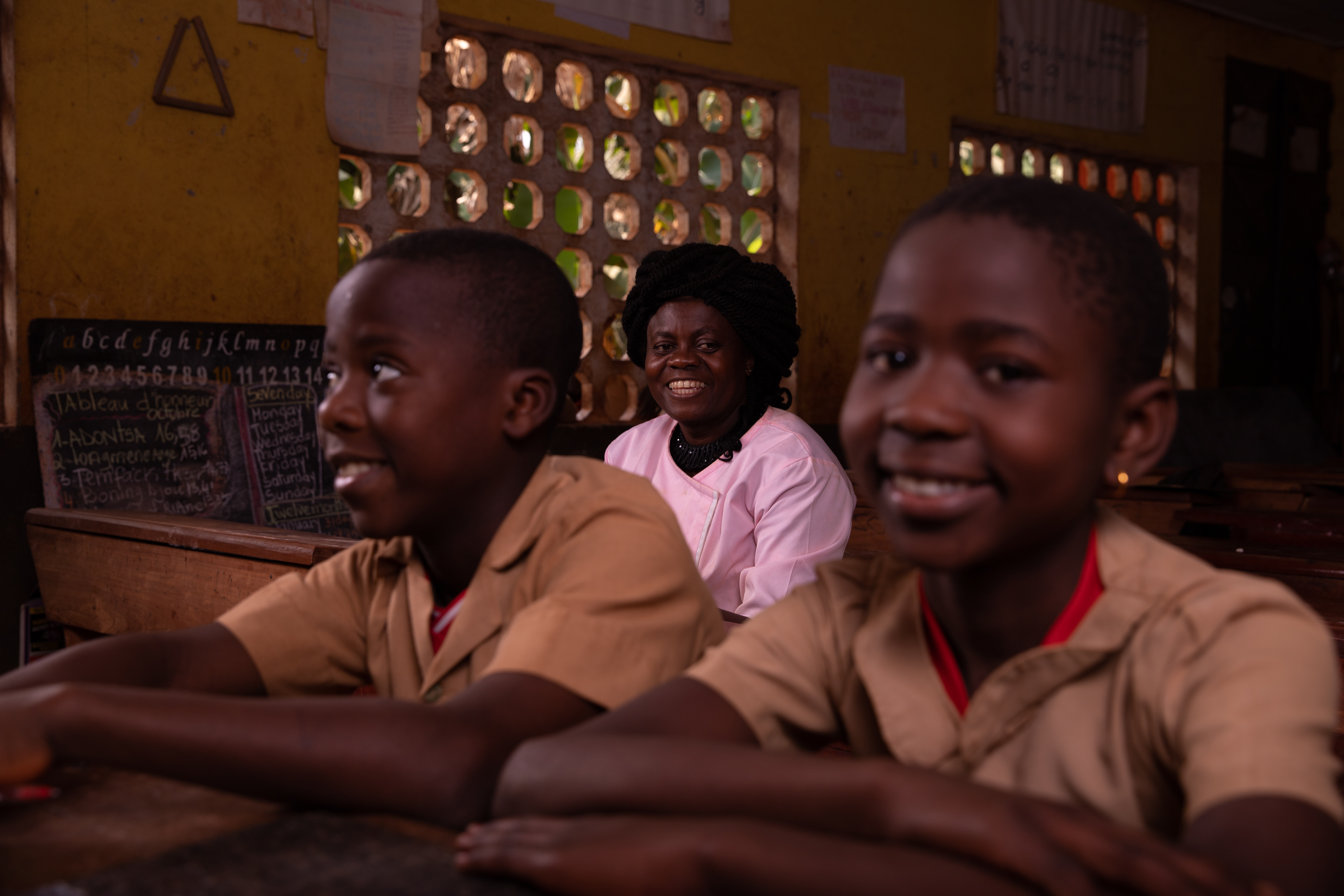 African teacher sitting in the classroom with her pupils.